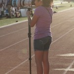 Junior Karla Estrada stands on her tip toes to capture an image behind the camera at a freshman football game. Despite having hearing issues and other health issues, she has found her niche in photography. (Cynthia Rangel photo)