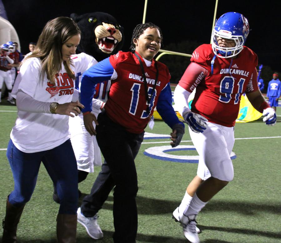 With the help of his physical therapist and the support of Panther lineman Sami Awad, sophomore Storm Malone runs out on the field for the first time after a domestic violence shooting left him in a coma over two years ago with no hope of walking again. (Cynthia Rangel photo)