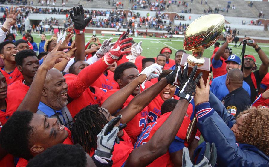 Duncanville Principal Tia Simmons presents the Regional Semi-Finals football trophy to Coach Reginald Samples and the team after their 32-27 win over Arlington Bowie. (Jose Sanchez photo)