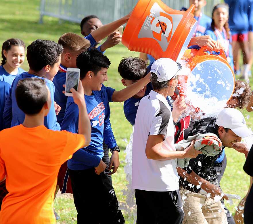 Runners smash assistant coach Moses Pena with ice water after the announcement of the teams district championship. (Ricardo Martin photo)