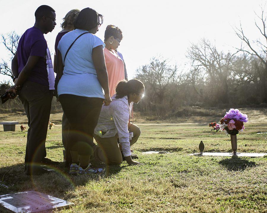 Senior Storm Malone kneels at the foot of his mother and sisters graves a few days after his mothers birthday. Every time he visits the grave he remembers the day four years ago when their lives were cut short in a tragic domestic violence shooting. Storm said he just wants to remember the joy they both brought to his life. (Alexis Rosebrock Photo)